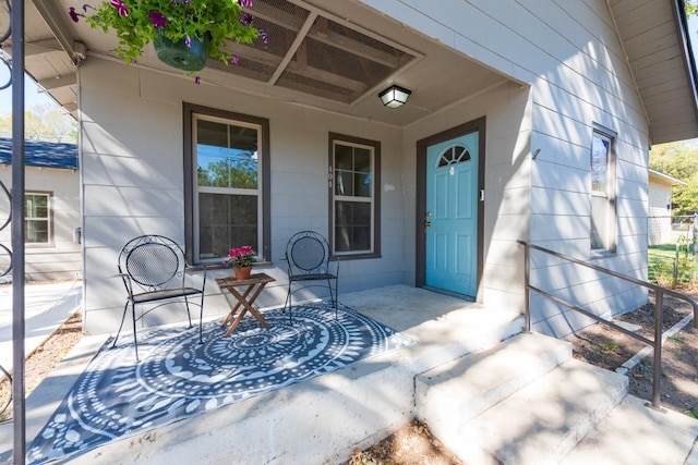 view of exterior entry featuring concrete block siding and a porch