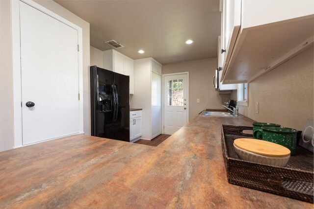 404 S Oak Ave, Luling, TX 78648 - kitchen with black refrigerator with ice dispenser, a sink, white cabinets, and recessed lighting
