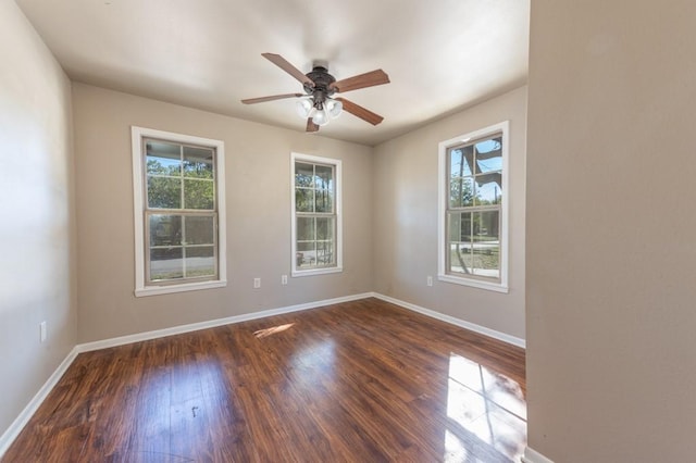 spare room featuring dark wood-style floors, ceiling fan, and baseboards