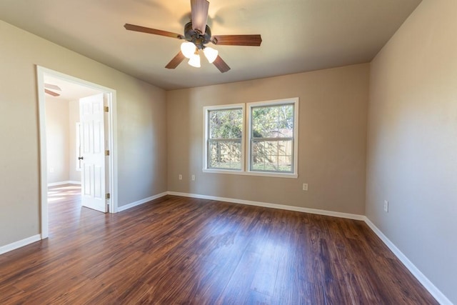 empty room featuring baseboards, dark wood finished floors, and a ceiling fan