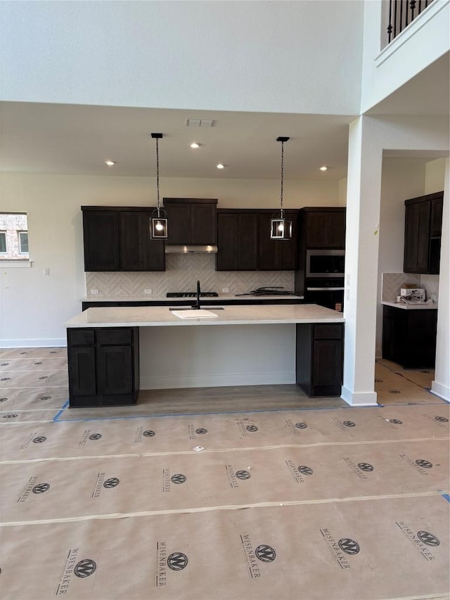 417 Hollister Dr, Liberty Hill, TX 78642 - kitchen with black oven, a sink, decorative backsplash, stainless steel microwave, and light countertops