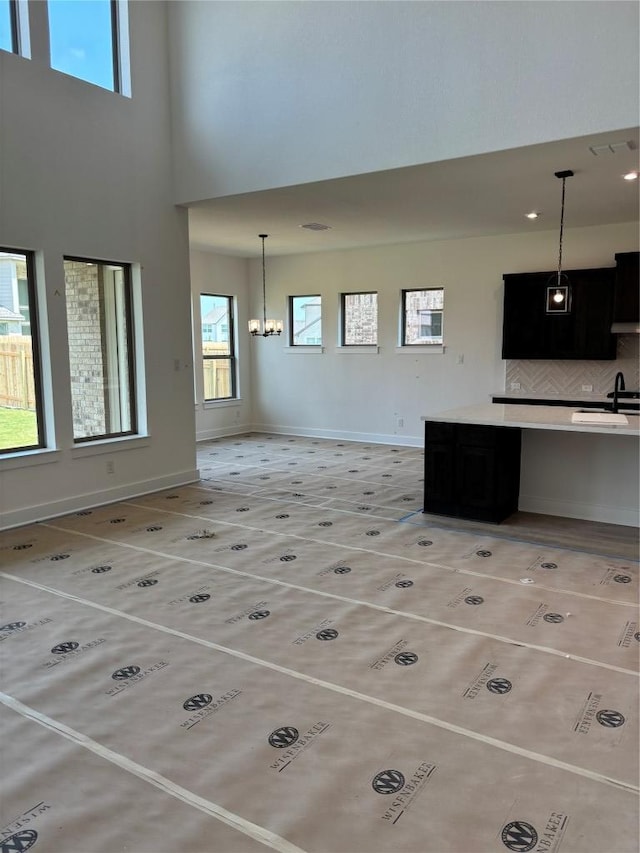 417 Hollister Dr, Liberty Hill, TX 78642 - unfurnished living room with a sink, a high ceiling, baseboards, and a chandelier