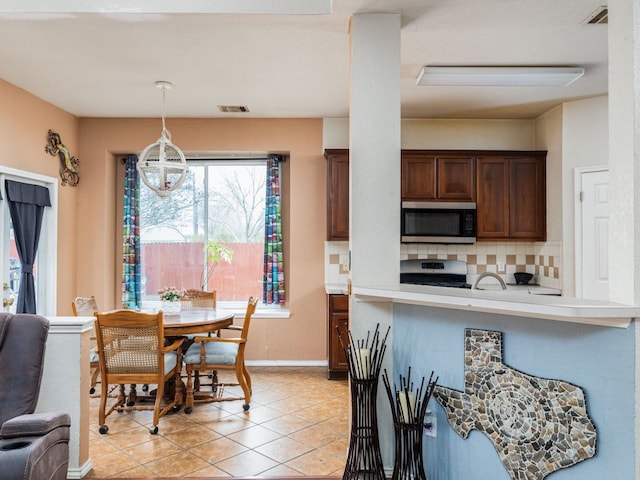 kitchen with tasteful backsplash, visible vents, appliances with stainless steel finishes, decorative light fixtures, and light countertops