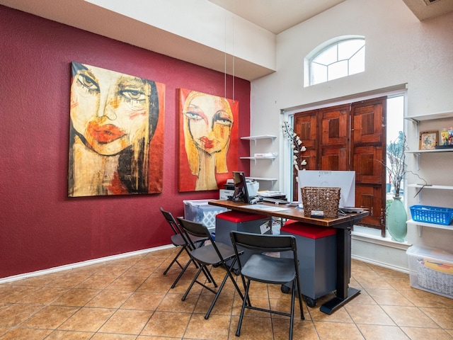 office space with a towering ceiling, tile patterned flooring, and baseboards