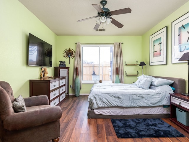 bedroom with dark wood-style floors, visible vents, baseboards, and a ceiling fan