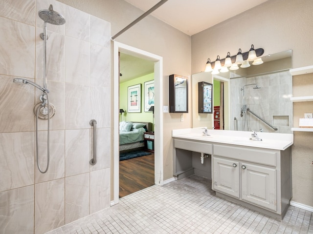 bathroom featuring double vanity, tiled shower, a sink, and ensuite bathroom