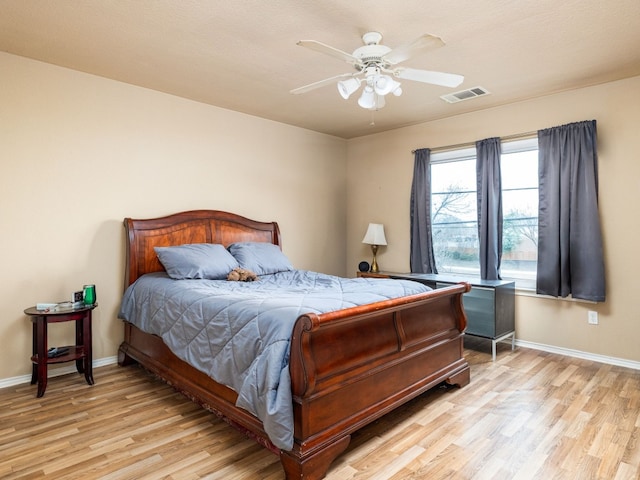 bedroom with a ceiling fan, light wood-type flooring, visible vents, and baseboards