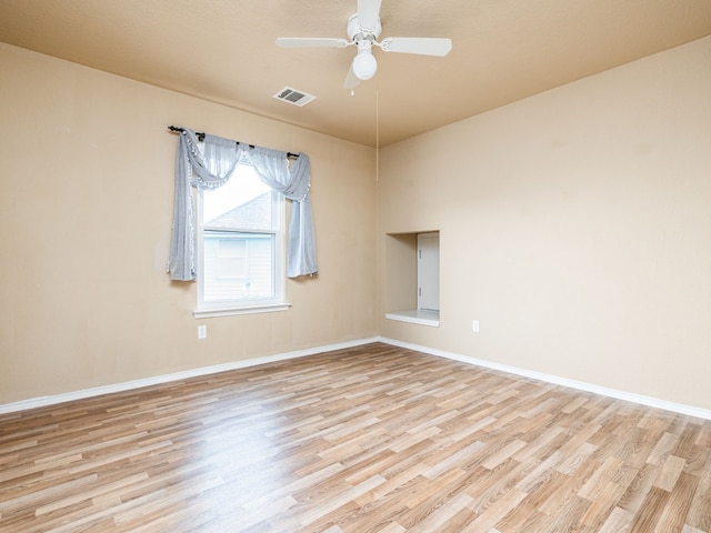 spare room featuring light wood-style floors, visible vents, ceiling fan, and baseboards