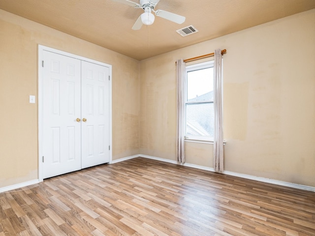 unfurnished bedroom featuring baseboards, visible vents, a ceiling fan, light wood-type flooring, and a closet