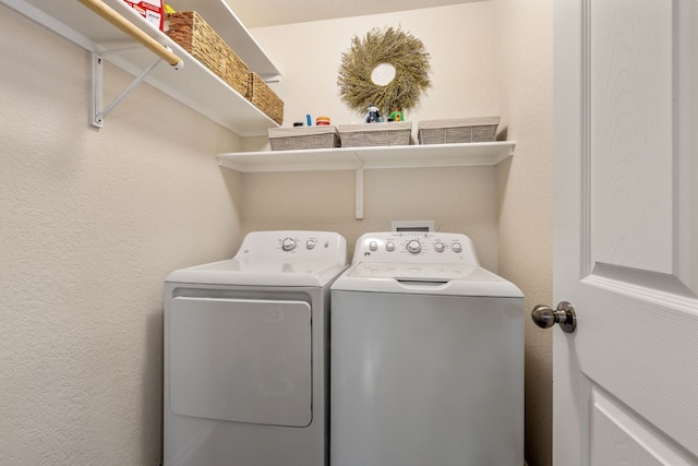 clothes washing area featuring laundry area, a textured wall, and independent washer and dryer