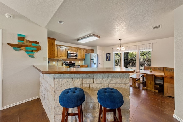 kitchen featuring a peninsula, visible vents, appliances with stainless steel finishes, and a breakfast bar area