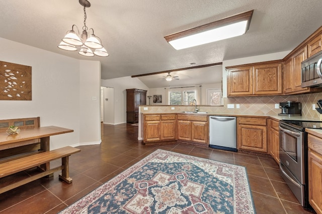 kitchen with appliances with stainless steel finishes, a peninsula, light countertops, pendant lighting, and backsplash