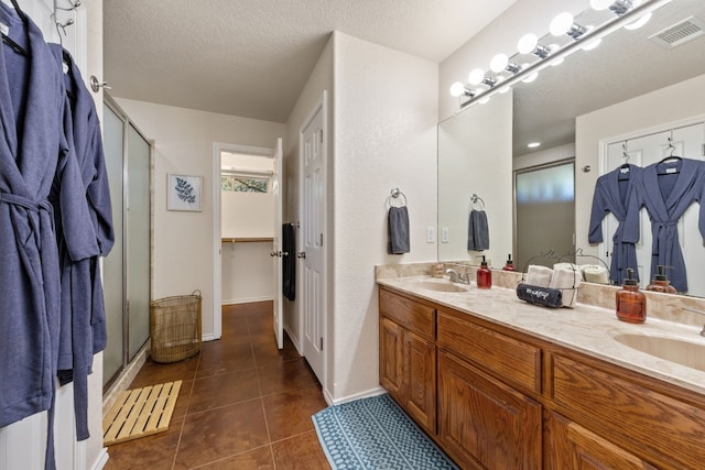 full bath with double vanity, visible vents, tile patterned floors, a shower stall, and a sink