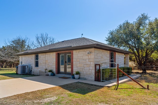 back of house with roof with shingles, a patio, fence, cooling unit, and stone siding