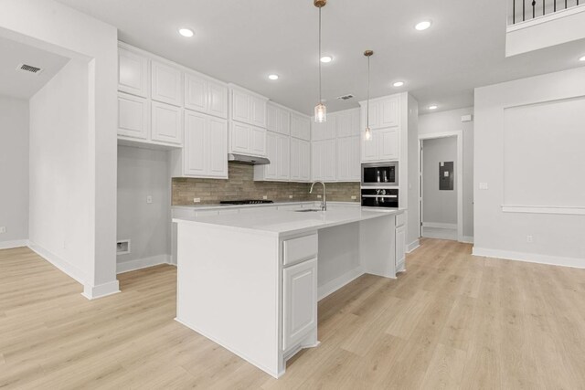 1109 Blanket Flower Dr, Georgetown, TX 78628 - kitchen with stainless steel microwave, black oven, white cabinets, tasteful backsplash, and light countertops
