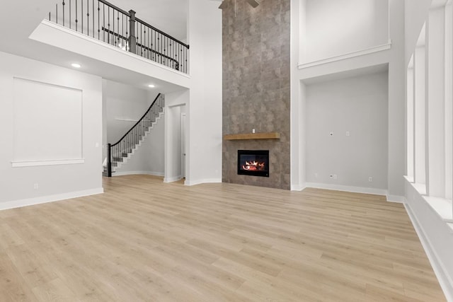 1109 Blanket Flower Dr, Georgetown, TX 78628 - unfurnished living room with a high ceiling, a fireplace, stairway, and light wood-style flooring