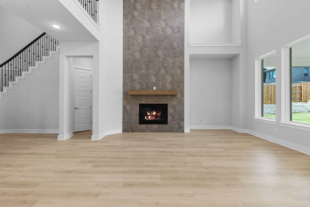 1109 Blanket Flower Dr, Georgetown, TX 78628 - unfurnished living room with a towering ceiling, light wood finished floors, a fireplace, and stairs
