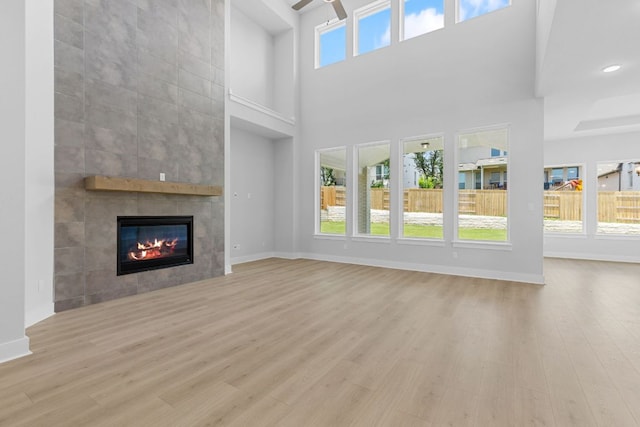 1109 Blanket Flower Dr, Georgetown, TX 78628 - unfurnished living room with ceiling fan, a fireplace, wood finished floors, and a towering ceiling