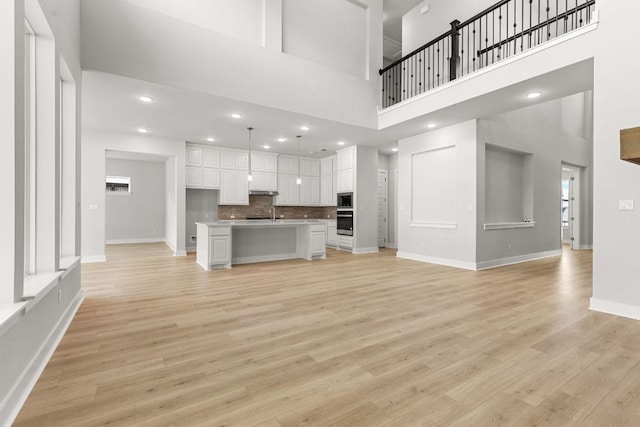 1109 Blanket Flower Dr, Georgetown, TX 78628 - unfurnished living room featuring a towering ceiling, light wood-style floors, and recessed lighting