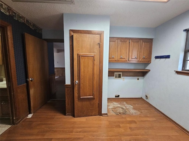 washroom featuring cabinet space, hookup for a washing machine, hookup for an electric dryer, a textured ceiling, and light wood-type flooring