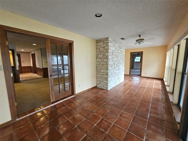 spare room with a textured ceiling, dark tile patterned flooring, visible vents, and a healthy amount of sunlight