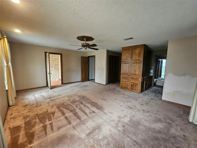 unfurnished bedroom featuring baseboards, visible vents, a ceiling fan, a textured ceiling, and carpet flooring