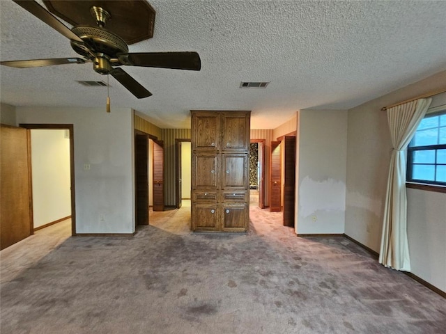 unfurnished bedroom with light carpet, a textured ceiling, visible vents, and baseboards