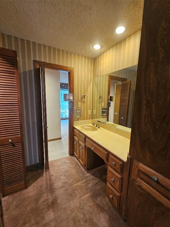 bathroom with recessed lighting, a textured ceiling, vanity, and wallpapered walls