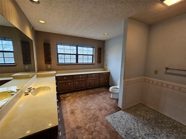 full bathroom featuring a textured ceiling, a garden tub, toilet, recessed lighting, and vanity