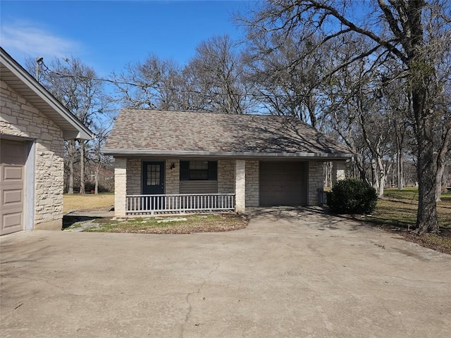 view of front of house with a garage, concrete driveway, stone siding, roof with shingles, and a porch