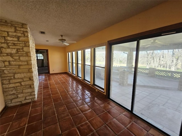 unfurnished sunroom with a ceiling fan and visible vents