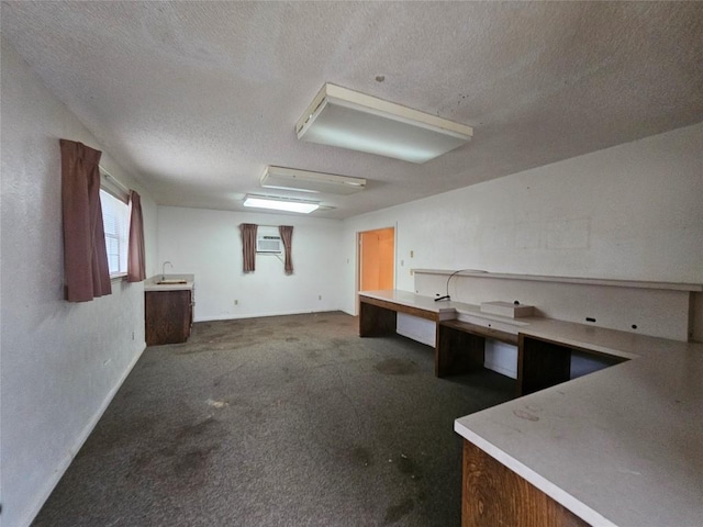 below grade area with a textured ceiling, dark colored carpet, and a sink