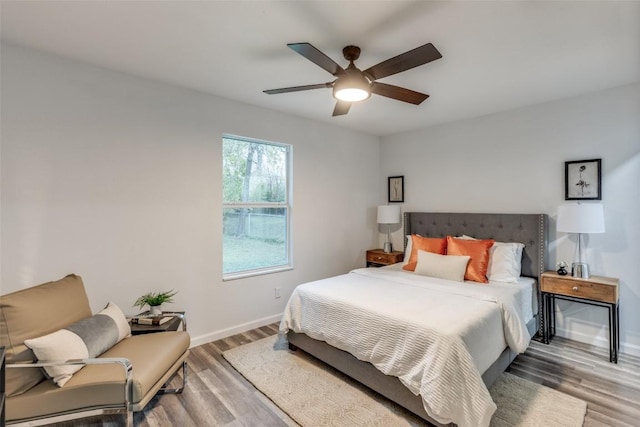 bedroom featuring ceiling fan, baseboards, and wood finished floors