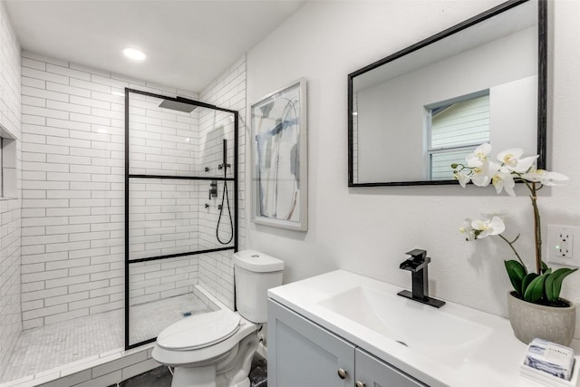 bathroom featuring toilet, a stall shower, and vanity