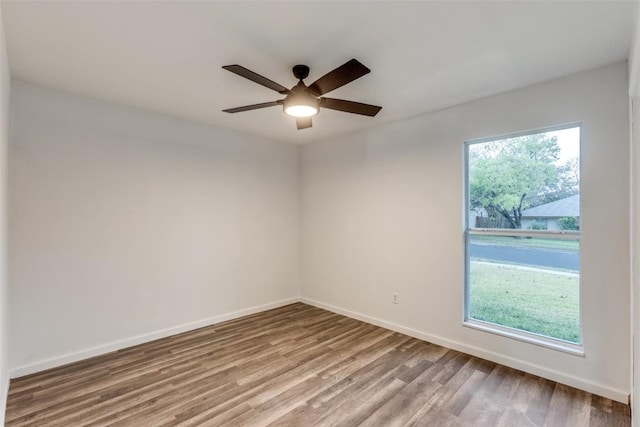 spare room featuring plenty of natural light, baseboards, and wood finished floors