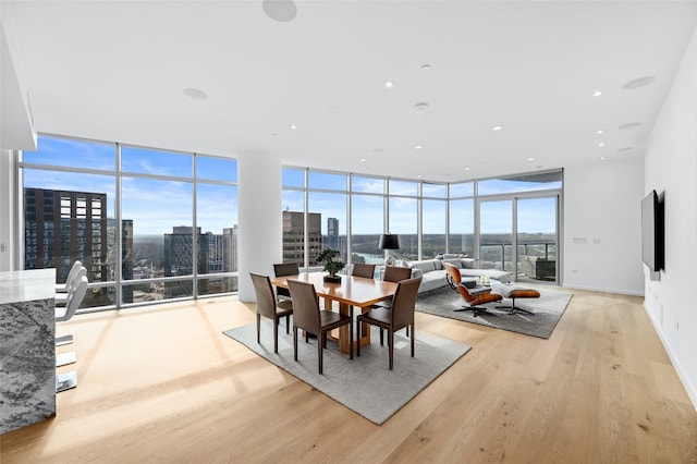 dining area with a city view, baseboards, light wood-style floors, a wealth of natural light, and floor to ceiling windows