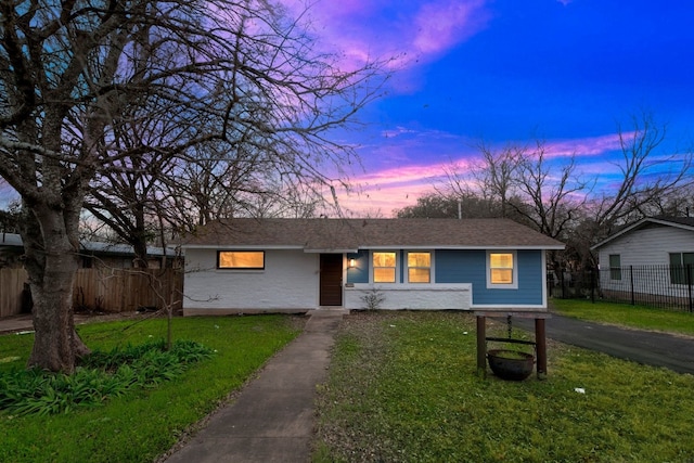 ranch-style house with a shingled roof, driveway, a front lawn, and fence