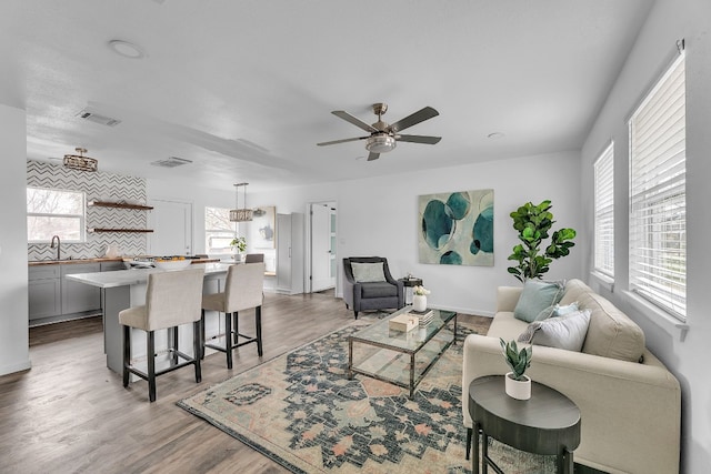 living area featuring ceiling fan, wood finished floors, and visible vents