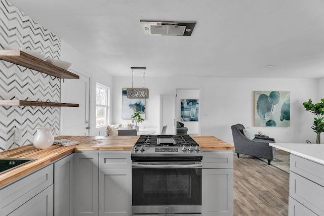 kitchen with open shelves, gas range, wooden counters, and decorative light fixtures