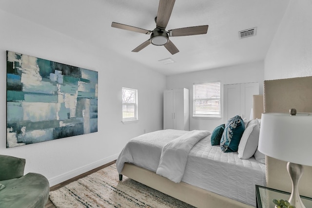 bedroom with baseboards, visible vents, ceiling fan, and wood finished floors