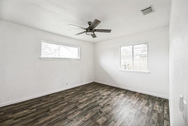 empty room with dark wood-style floors, baseboards, visible vents, and a ceiling fan