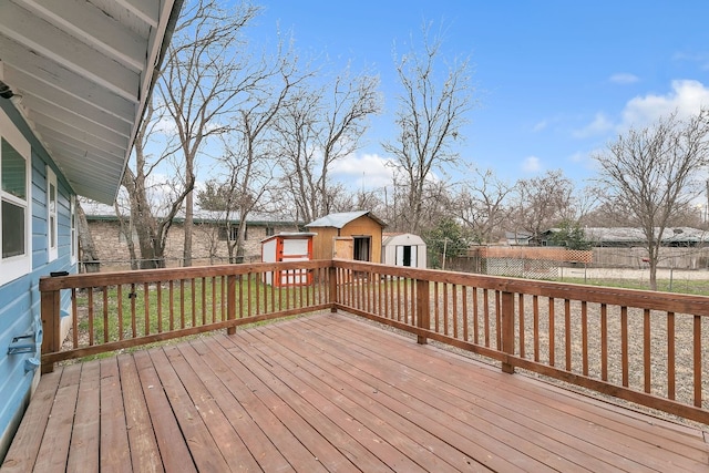 wooden terrace with a storage shed, a fenced backyard, a yard, and an outdoor structure