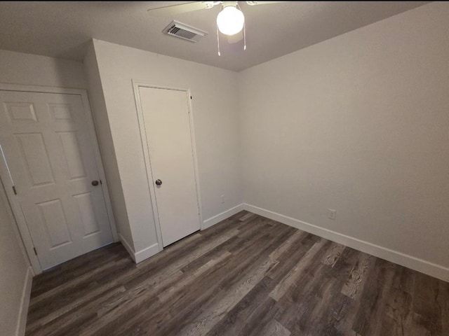 unfurnished bedroom with visible vents, dark wood finished floors, baseboards, and ceiling fan