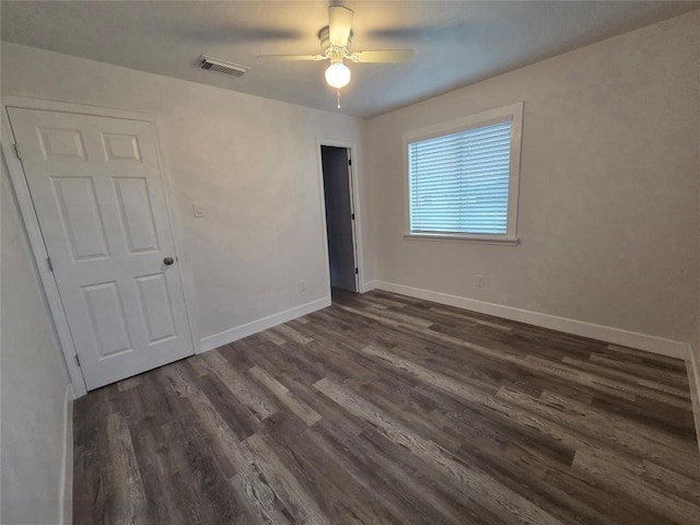 spare room featuring dark wood-style floors, visible vents, baseboards, and ceiling fan