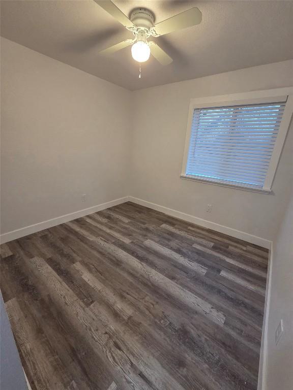 empty room featuring dark wood-type flooring, ceiling fan, and baseboards