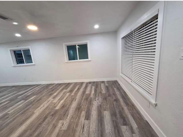 unfurnished room with baseboards, visible vents, dark wood-style flooring, and recessed lighting