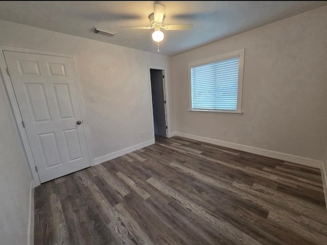 unfurnished room with a ceiling fan, dark wood-style flooring, visible vents, and baseboards