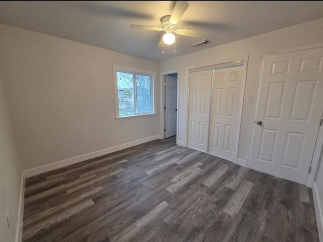 unfurnished bedroom featuring baseboards, visible vents, ceiling fan, dark wood-type flooring, and a closet