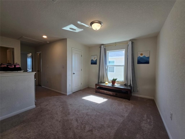 unfurnished bedroom with dark carpet, a textured ceiling, and baseboards