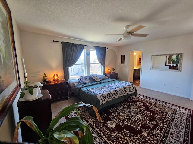 bedroom with carpet floors, arched walkways, and a textured ceiling